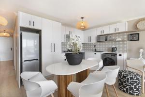 a white kitchen with a table and white chairs at Coral Island 204 in Bloubergstrand