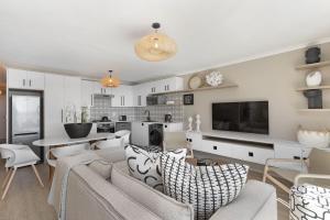a living room with a couch and chairs and a tv at Coral Island 204 in Bloubergstrand