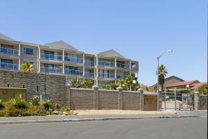 an apartment building with a brick wall and a fence at Coral Island 204 in Bloubergstrand