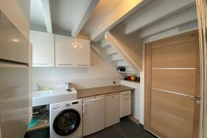 eine Küche mit weißen Schränken, einer Waschmaschine und einem Trockner in der Unterkunft Gîte dans les Vosges Gite du Feing des Loges in Vagney