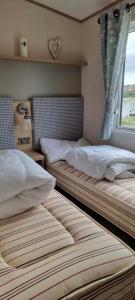 two twin beds in a room with a window at Littlesea-wv55 Weymouth in Wyke Regis