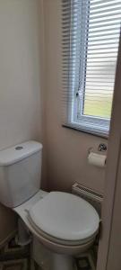 a bathroom with a white toilet and a window at Littlesea-wv55 Weymouth in Wyke Regis +2 photos