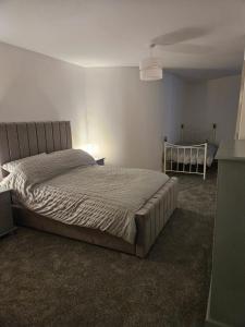 a bedroom with a bed and a crib at Luxury 2x Bedroom (3x Beds - Sleeps 5) & 1x Bathroom Apartment (Shower & Bath) in Cardiff
