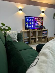 a living room with a green couch and a tv at Harrys Home - Weekly & Monthly Offers - Near NEC - Contractors & Business professionals - 2 Parking spaces - 4 Large Bedrooms & 2 Bathrooms - Pool - Table Tennis - Darts - Games console in Wyken