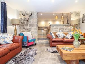 a living room with leather furniture and a stone wall at La Petit Maison in Saint Columb Major