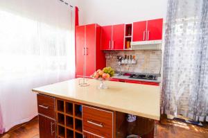 a kitchen with red cabinets and a vase of fruit on a counter at Villa Fialofana 