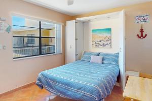 a bedroom with a bed with a blue comforter and a window at The Boardwalker in Hollywood