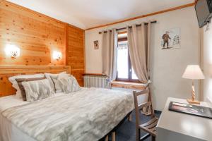 a bedroom with a bed and a desk and a window at Logis Hôtel et Spa Le Christiania in La Salle-les-Alpes