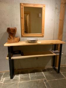 - une étagère en bois avec un miroir et un vase dans l'établissement CaLegna Ferienchalet, à Bad Kohlgrub