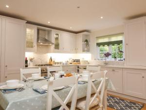 a kitchen with a table and chairs and a kitchen with white cabinets at Bay Tree Cottage in Kingsbridge
