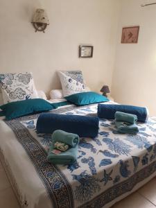 Bett mit blauer und weißer Bettwäsche und Kissen in der Unterkunft La Maison de Jenny in Montauroux