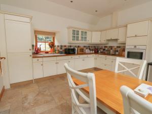 a kitchen with a wooden table and white cabinets at The Milk House in Fortrose