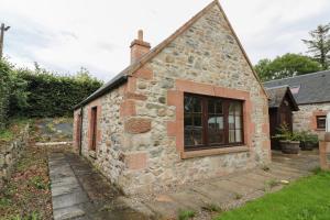 an old stone house with a window on the side at The Milk House in Fortrose