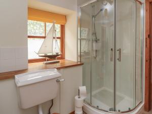 a bathroom with a toilet and a shower with a sailboat in a window at The Milk House in Fortrose