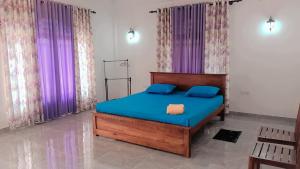 een slaapkamer met een bed met blauwe lakens en paarse gordijnen bij Sunrise Relax Inn in Beruwala