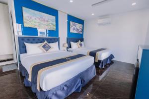ARINA HOTEL في Tây Ninh: سريرين في غرفة فندق بجدران زرقاء