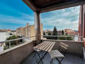 a wooden bench and two chairs on a balcony at Comfortable apartment in Viana do Castelo in Viana do Castelo