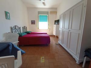 1 dormitorio con cama roja y ventana en Casa dei Glicini, en Nardò