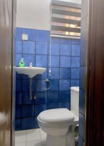 a blue tiled bathroom with a toilet and a sink at RUDISH COTTAGE (COZY & PRIVATE) in Abuja