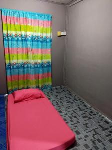 a room with a red bed in front of a curtain at LD SWEET HOMESTAY LAHAD DATU in Lahad Datu