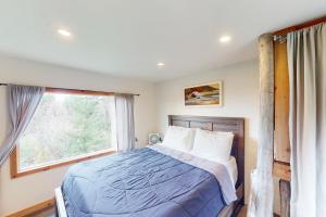 een slaapkamer met een bed en een raam bij Hummingbird Hideout in Port Orford
