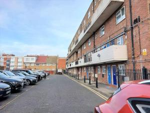 parking z samochodami zaparkowanymi obok ceglanego budynku w obiekcie 3 bedroom Flat in Hoxton London w Londynie