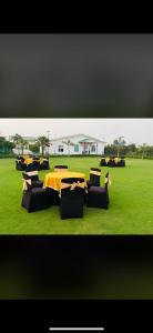 um grupo de mesas e cadeiras num campo verde em MB farms em Greater Noida