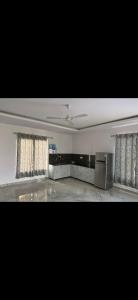 um quarto vazio com duas janelas com cortinas e um quarto com um fogão em MB farms em Greater Noida