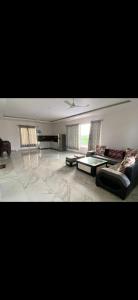 a living room with two couches and a table at MB farms in Greater Noida
