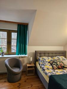 a bedroom with a bed and a chair and a window at Karczma Regionalna Młyn -pokoje gościne in Zwierzyniec