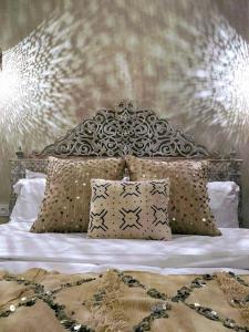 ein Bett mit verziertem Kopfteil und Kissen in der Unterkunft Riad with Outdoor Swimming Pools in Marrakesch