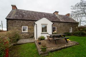 een stenen huis met een picknicktafel ervoor bij Brosnan's Cottage in Dingle