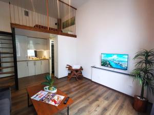 a living room with a table and a tv on a wall at Loft Apartment in Klaipėda