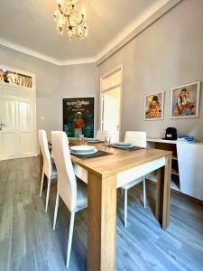 uma sala de jantar com uma mesa de madeira e cadeiras brancas em Le Parisien - Chic 2BR City Centre Escape em Tânger