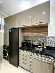 a kitchen with a black refrigerator and a microwave at Le Parisien - Chic 2BR City Centre Escape in Tangier