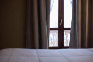 Una cama frente a una ventana con botellas. en Hotel La Fertè, en Asti