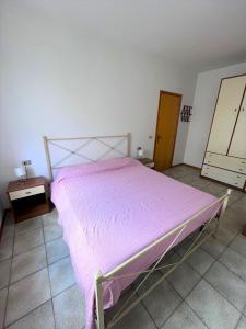 シローロにあるGIULY - appartamenti con terrazzo in centro a Siroloのベッドルーム1室(ピンクの毛布付きのベッド1台付)