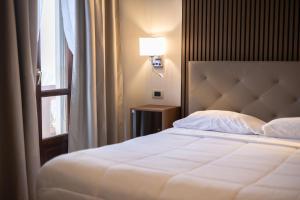 - une chambre avec un lit blanc et une fenêtre dans l'établissement Hotel La Fertè, à Asti