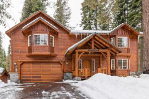 a log home with a garage in the snow at Tahoe Grand on the West Shore - Pet Friendly & Hot Tub! in Homewood