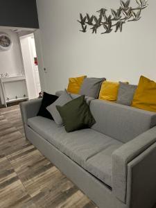a gray couch with yellow pillows in a living room at Overwave Apartment in Kavála