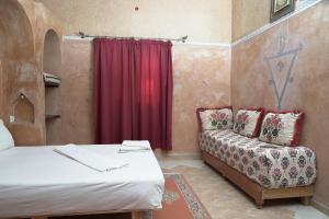 Cette chambre comprend un lit, un canapé et un rideau rouge. dans l'établissement CHEZ MANAR, à Ouarzazate