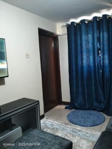 een woonkamer met een blauw gordijn en een tv bij Christie's apartments Buruburu in Nairobi