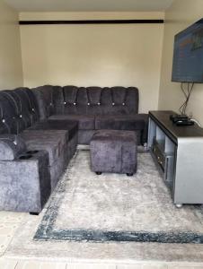 een woonkamer met een leren bank en een tv bij Christie's apartments Buruburu in Nairobi