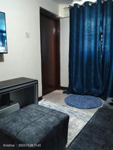 een kamer met een bed en een blauw gordijn bij Christie's apartments Buruburu in Nairobi