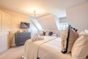 a bedroom with a large white bed and a tv at Elegant 4-Bed Home,Private Garden,Parking in Virginia Water