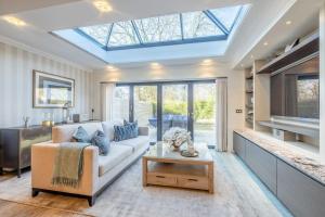 a living room with a white couch and a skylight at Elegant 4-Bed Home,Private Garden,Parking in Virginia Water