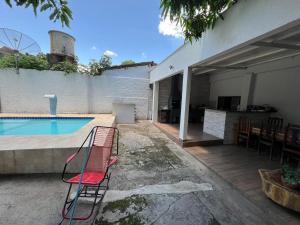 a swimming pool with a red chair next to a house at Hostel Dourado in Barra do Garças