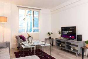 a living room with a couch and a tv at 3-Bed Apartment Central London - 15 Mins walk to Kings Cross by Seren Short Stays in London