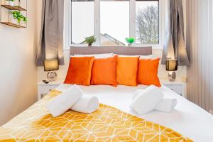 a bedroom with a large bed with orange and white pillows at Cosy 3 Bedroom House with Free Parking and Garden in Earley