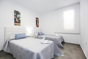 two beds in a room with white walls at NEW VALENCIA 2 Planetcostadorada in Salou